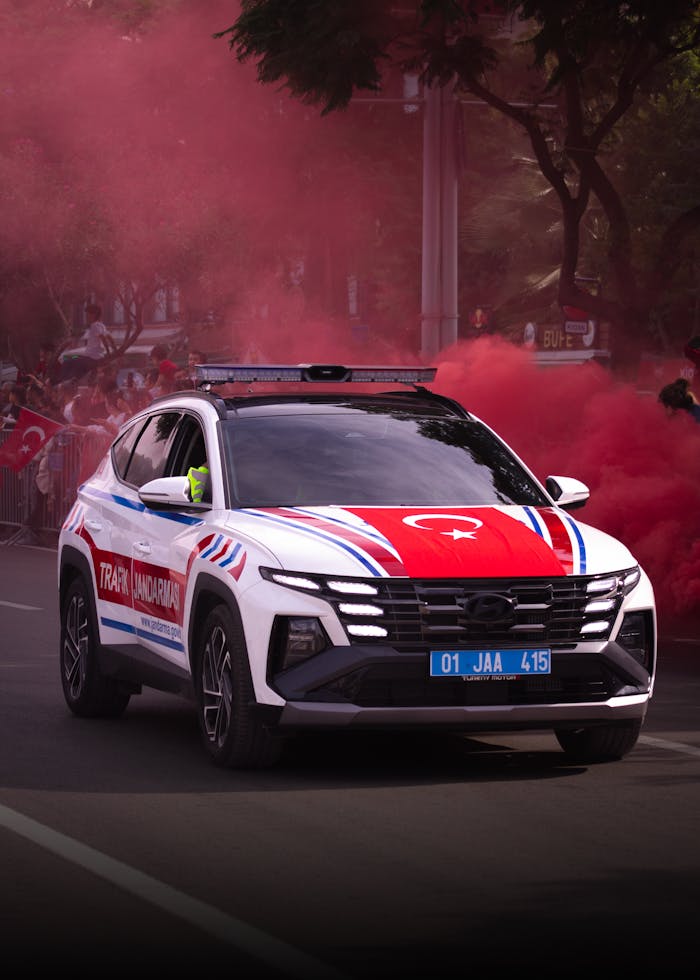 A Turkish traffic police car surrounded by red smoke during a parade in Adana, Türkiye.